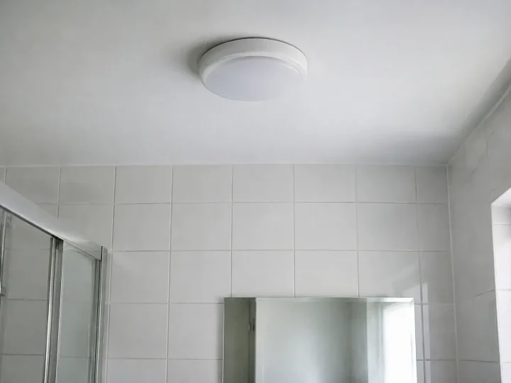 Luminaire rond blanc au plafond, mur carrele blanc