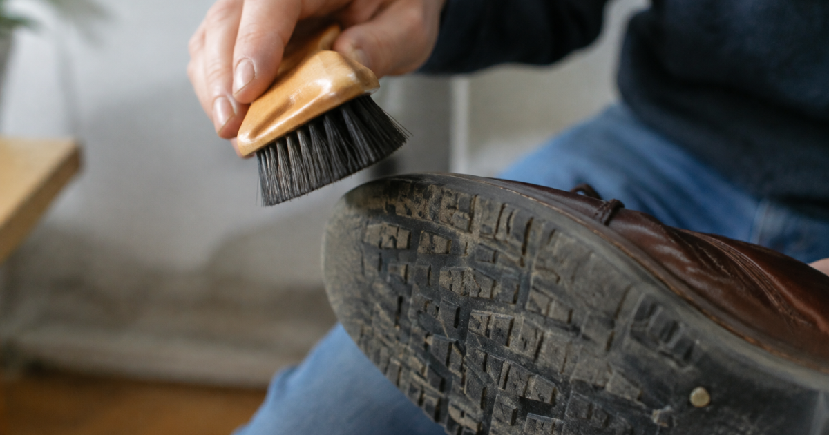Main tenant une brosse au-dessus d'une semelle chaude