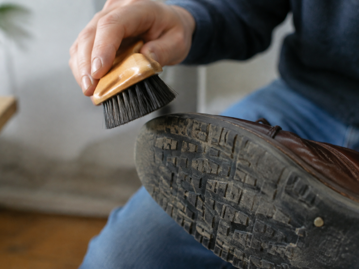 Main tenant une brosse au-dessus d'une semelle chaude